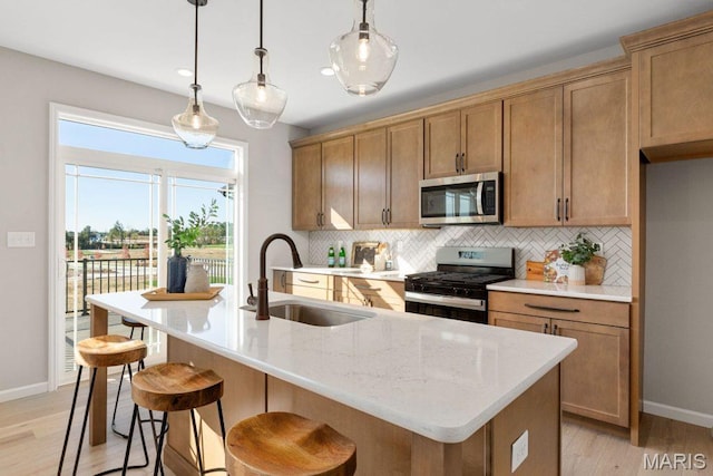 543 Wheatfield Cir, Ofallon, MO 63385 - kitchen featuring appliances with stainless steel finishes, a sink, tasteful backsplash, light wood-style flooring, and baseboards