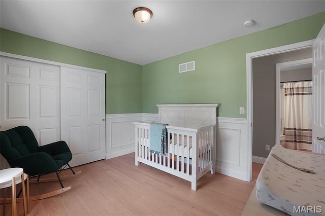 3837 Bedford Pointe Dr, Wentzville, MO 63385 - bedroom with a wainscoted wall, light wood-type flooring, a closet, a decorative wall, and a nursery area