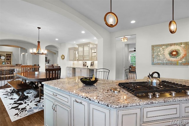 1316 Breezeridge Dr, Des Peres, MO 63131 - kitchen with arched walkways, stainless steel gas cooktop, dark wood finished floors, light stone countertops, and recessed lighting