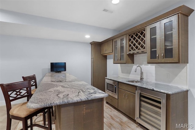 1316 Breezeridge Dr, Des Peres, MO 63131 - indoor wet bar with wine cooler, stainless steel microwave, recessed lighting, and light wood finished floors