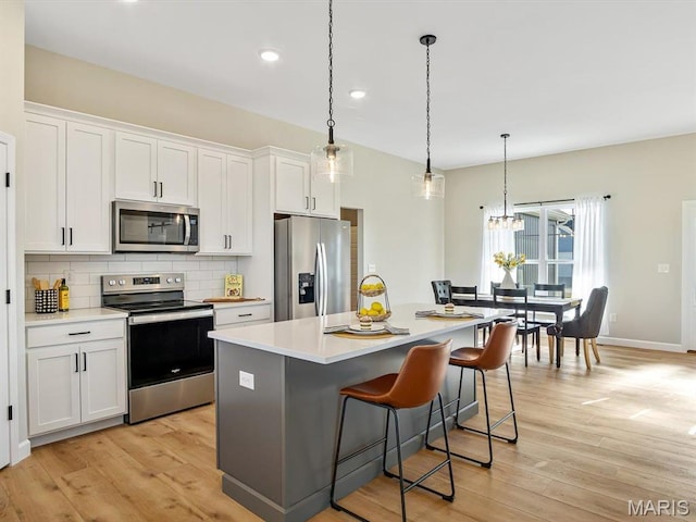 484 Hayden Dr, Waterloo, IL 62298 - kitchen featuring appliances with stainless steel finishes, decorative backsplash, white cabinets, a kitchen island, and light wood finished floors