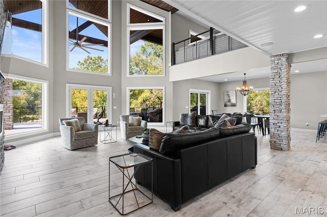 2262 Brown Rd, Van Buren, MO 63965 - living area featuring decorative columns, ceiling fan, a chandelier, light wood-style flooring, and a towering ceiling