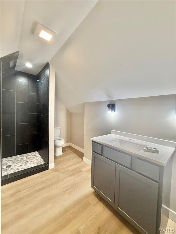 500 W Pacific St, Pacific, MO 63069 - bathroom with wood finished floors, a tile shower, vaulted ceiling, and vanity