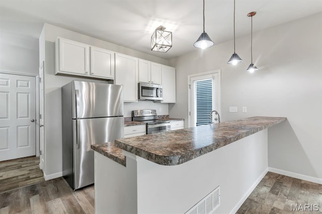 109 Starry Night Way, Saint Charles, MO 63301 - kitchen featuring stainless steel appliances, a peninsula, dark countertops, dark wood-style flooring, and white cabinetry