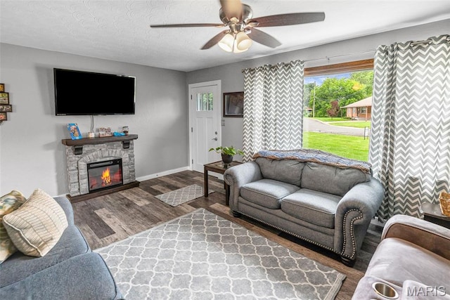 415 Virginia Ave, Cottage Hills, IL 62018 - living area with plenty of natural light, a ceiling fan, wood finished floors, a stone fireplace, and a textured ceiling