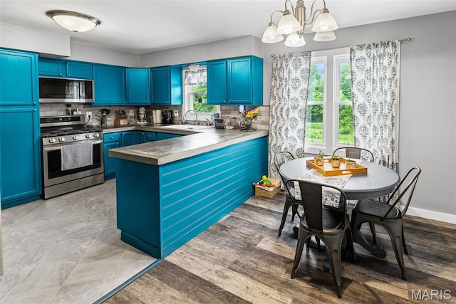 415 Virginia Ave, Cottage Hills, IL 62018 - kitchen with stainless steel appliances, a sink, a chandelier, blue cabinetry, and backsplash