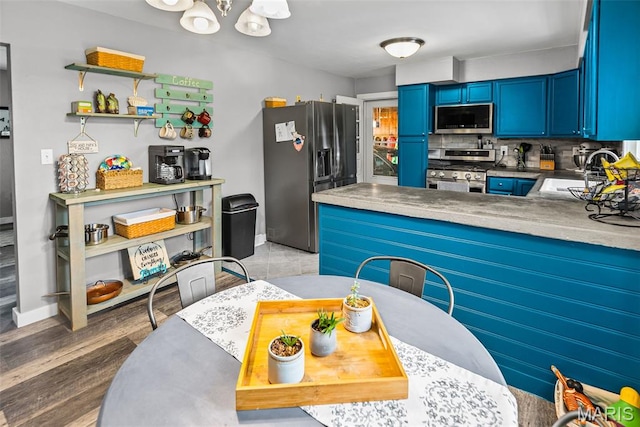415 Virginia Ave, Cottage Hills, IL 62018 - kitchen featuring appliances with stainless steel finishes, blue cabinetry, a sink, tasteful backsplash, and baseboards