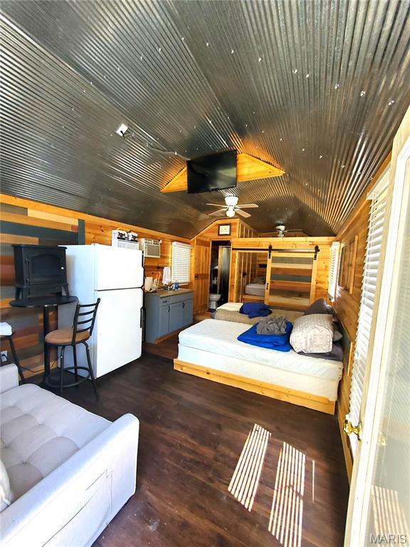 303 Arrowhead Trl, Hermann, MO 65041 - bedroom featuring freestanding refrigerator, wooden walls, wood finished floors, and vaulted ceiling