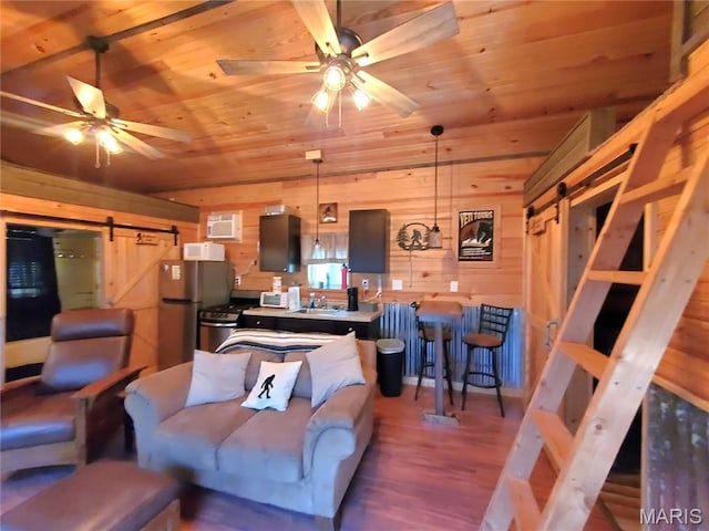 303 Arrowhead Trl, Hermann, MO 65041 - living room featuring a barn door, wood ceiling, wooden walls, ceiling fan, and wood finished floors