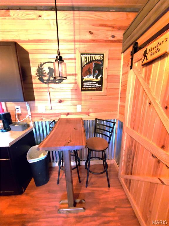 303 Arrowhead Trl, Hermann, MO 65041 - dining room with wooden walls, wood finished floors, and a barn door