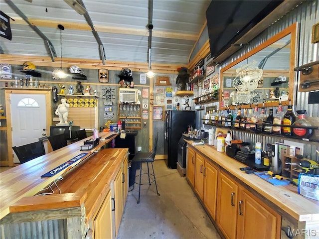 303 Arrowhead Trl, Hermann, MO 65041 - indoor dry bar featuring concrete flooring, hanging light fixtures, freestanding refrigerator, and a workshop area