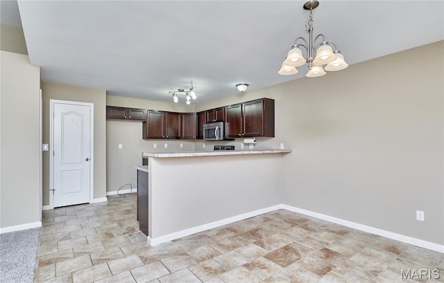 628 Meadowgreen Dr, Troy, MO 63379 - kitchen with stainless steel microwave, dark brown cabinets, a chandelier, stone finish floors, and a peninsula