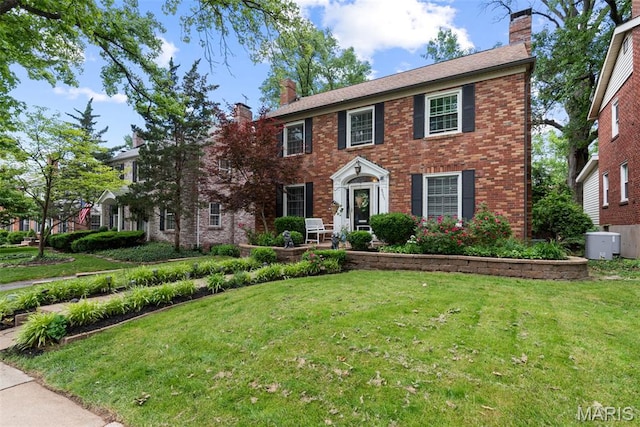 9351 White Ave, Brentwood, MO 63144 - colonial-style house with a chimney, a front yard, and brick siding