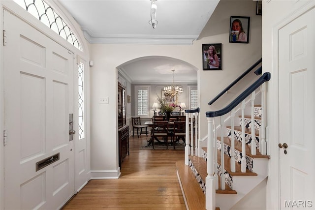 9351 White Ave, Brentwood, MO 63144 - entryway with ornamental molding, arched walkways, light wood finished floors, stairway, and a chandelier