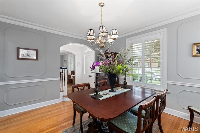 9351 White Ave, Brentwood, MO 63144 - dining space with arched walkways, light wood-style flooring, a chandelier, ornamental molding, and baseboards