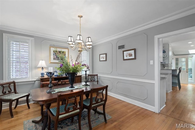 9351 White Ave, Brentwood, MO 63144 - dining area featuring ornamental molding, a chandelier, light wood finished floors, and a decorative wall