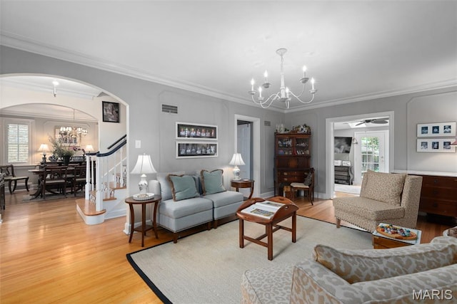 9351 White Ave, Brentwood, MO 63144 - living room featuring a chandelier, arched walkways, light wood finished floors, ornamental molding, and stairway