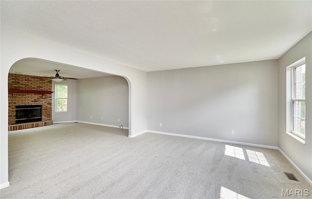 1583 Clarys Grv, Ofallon, IL 62269 - unfurnished living room with arched walkways, carpet, a ceiling fan, baseboards, and a fireplace