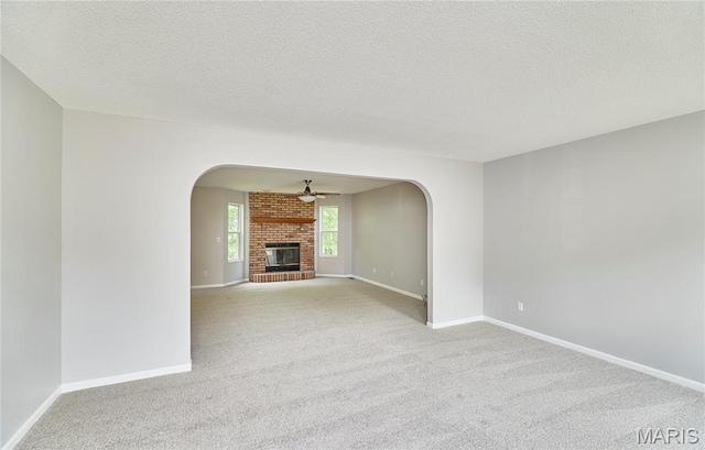 1583 Clarys Grv, Ofallon, IL 62269 - unfurnished living room featuring arched walkways, carpet flooring, ceiling fan, baseboards, and a textured ceiling