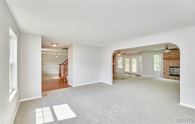 1583 Clarys Grv, Ofallon, IL 62269 - unfurnished living room with a ceiling fan, a brick fireplace, carpet floors, arched walkways, and baseboards