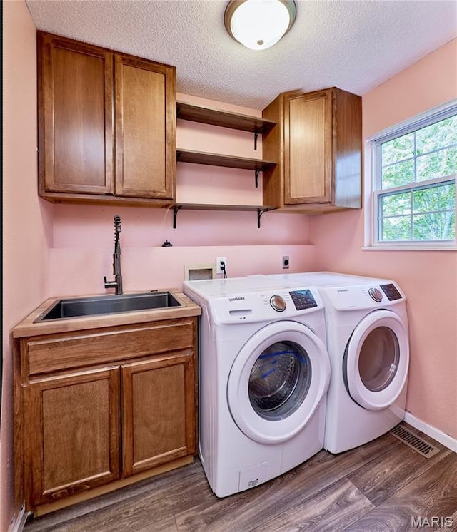 1583 Clarys Grv, Ofallon, IL 62269 - laundry room with cabinet space, washer and dryer, wood finished floors, a textured ceiling, and baseboards