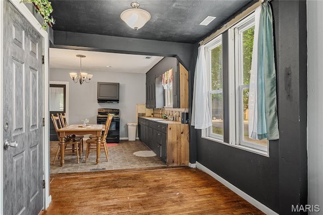 330 Elliott Ave, Chaffee, MO 63740 - kitchen with range with electric stovetop, wood finished floors, a chandelier, baseboards, and tasteful backsplash
