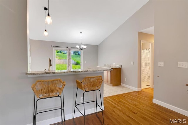 612 Hill Dr, Eureka, MO 63025 - kitchen featuring lofted ceiling, light wood-style floors, a breakfast bar, a chandelier, and pendant lighting