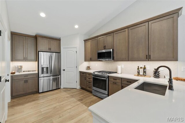 7405 Shadow Point Dr, Saint Louis, MO 63129 - kitchen featuring stainless steel appliances, a sink, decorative backsplash, lofted ceiling, and light wood finished floors