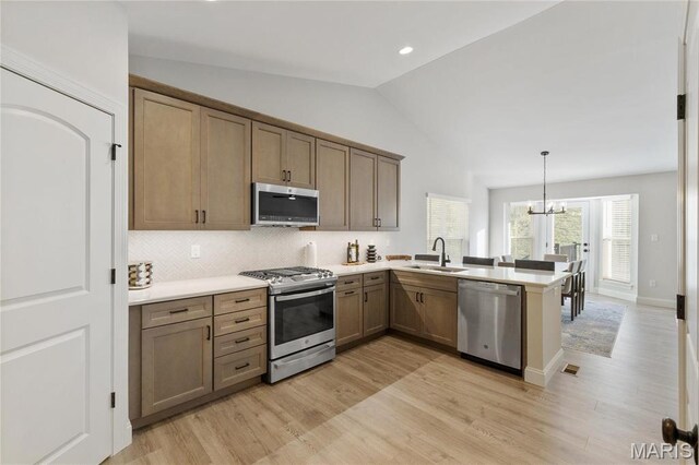 7405 Shadow Point Dr, Saint Louis, MO 63129 - kitchen with appliances with stainless steel finishes, a sink, lofted ceiling, a peninsula, and backsplash