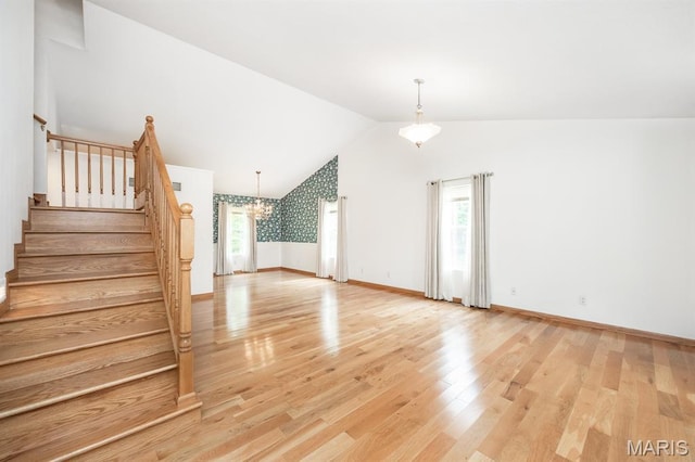 608 Andra Dr, Maryville, IL 62062 - unfurnished living room with lofted ceiling, light wood-style floors, a chandelier, stairs, and baseboards