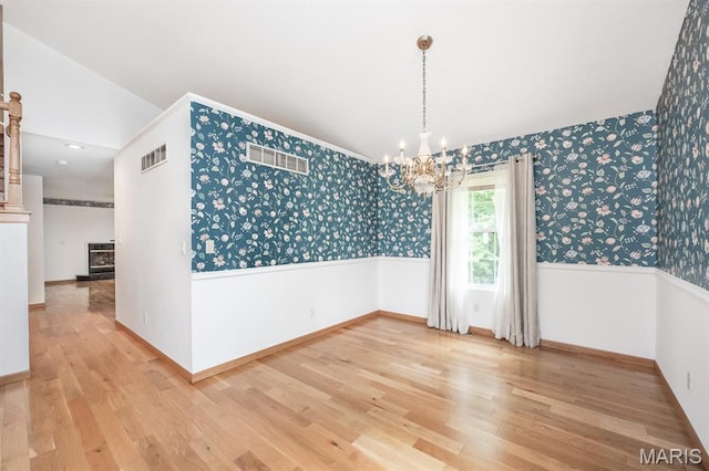 608 Andra Dr, Maryville, IL 62062 - unfurnished dining area with wallpapered walls, a chandelier, light wood finished floors, baseboards, and vaulted ceiling