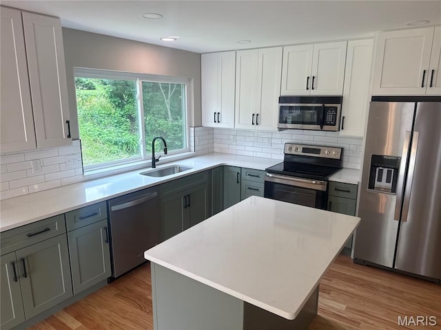 2542 Dukeland Dr, Ferguson Township, MO 63136 - kitchen with stainless steel appliances, a sink, light countertops, decorative backsplash, and light wood-style floors