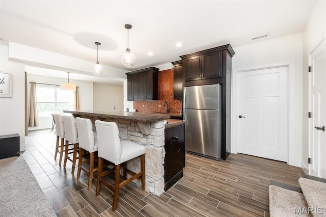 1821 Orr Ln, Ofallon, IL 62269 - kitchen with freestanding refrigerator, dark brown cabinets, a breakfast bar, wood finish floors, and a kitchen island