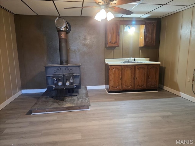 18835 Mary Jane Ln, Carlyle, IL 62231 - kitchen with light wood-type flooring, a ceiling fan, a sink, a wood stove, and baseboards