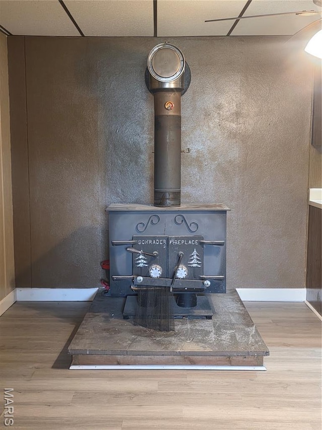18835 Mary Jane Ln, Carlyle, IL 62231 - detailed view of a wood stove, wood finished floors, a drop ceiling, and baseboards