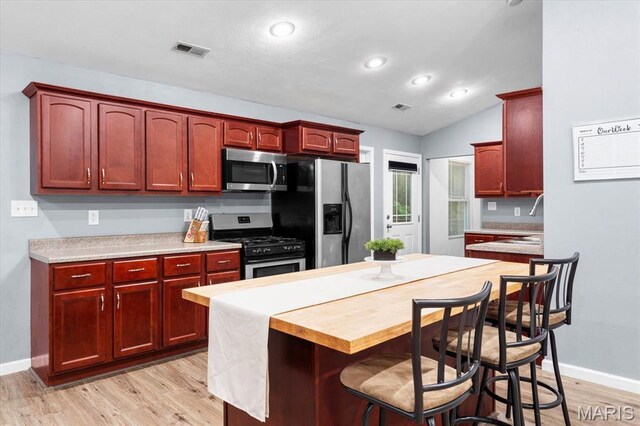 9138 Lynwood Ln, Fairview Heights, IL 62208 - kitchen featuring stainless steel appliances, reddish brown cabinets, light wood-style floors, light countertops, and vaulted ceiling