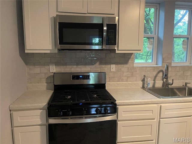 1432 Tamerton Ave, Overland, MO 63132 - kitchen with stainless steel appliances, light countertops, backsplash, and white cabinets