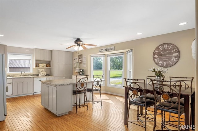 795 Schluersburg Rd, Augusta, MO 63332 - kitchen featuring dishwasher, a kitchen island, a sink, a breakfast bar area, and light wood finished floors