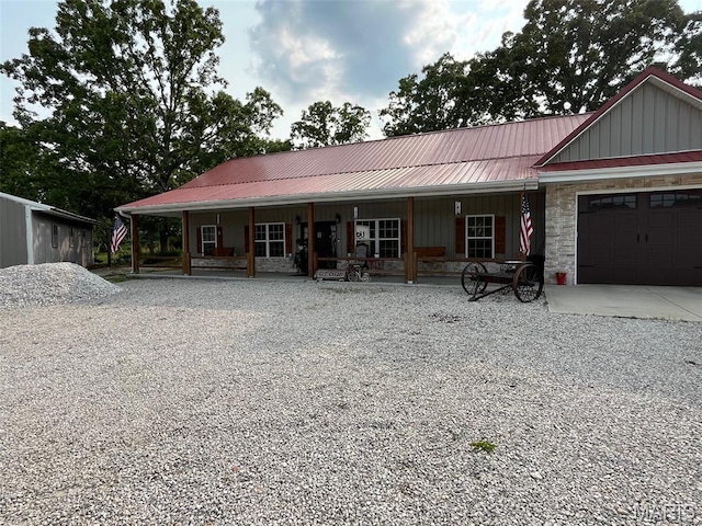 10570 Old 8 E, Mineral Point, MO 63660 - view of front of home with a porch, board and batten siding, metal roof, gravel driveway, and a garage