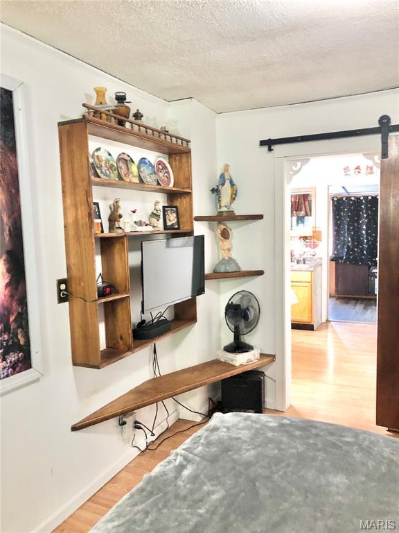 1003 W Ellis St, Salem, MO 65560 - home office with a barn door, wood finished floors, a textured ceiling, and baseboards