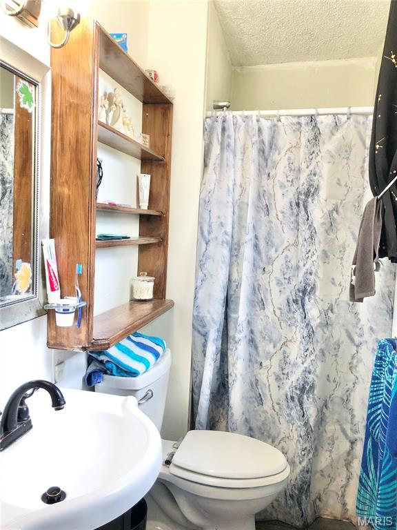 1003 W Ellis St, Salem, MO 65560 - full bathroom featuring a sink, toilet, a textured ceiling, and a shower with curtain