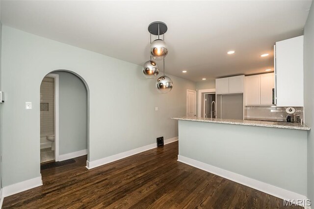 3271 Alfred Ave, Saint Louis, MO 63116 - kitchen with arched walkways, light stone counters, recessed lighting, a peninsula, and white cabinetry