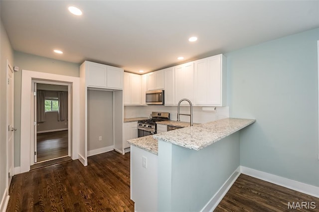 3271 Alfred Ave, Saint Louis, MO 63116 - kitchen featuring appliances with stainless steel finishes, light stone counters, a peninsula, white cabinets, and dark wood-style flooring