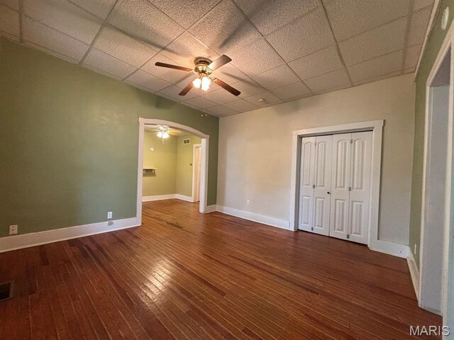 410 S Main St, Monroe City, MO 63456 - unfurnished bedroom featuring a drop ceiling, arched walkways, dark wood-style floors, a closet, and ceiling fan