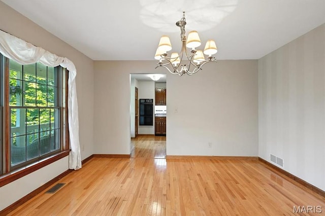 18232 Prickly Pear Ct, Pacific, MO 63069 - spare room featuring light wood-style flooring, a chandelier, and wallpapered walls