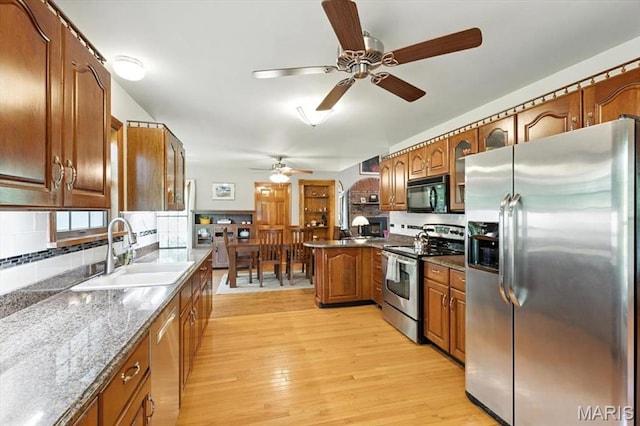 18232 Prickly Pear Ct, Pacific, MO 63069 - kitchen featuring stainless steel appliances, a ceiling fan, brown cabinets, backsplash, and light wood-style floors