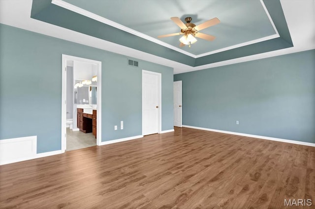 1609 10th Fairway Dr, Belleville, IL 62220 - unfurnished bedroom featuring a tray ceiling, wood finished floors, connected bathroom, and a ceiling fan