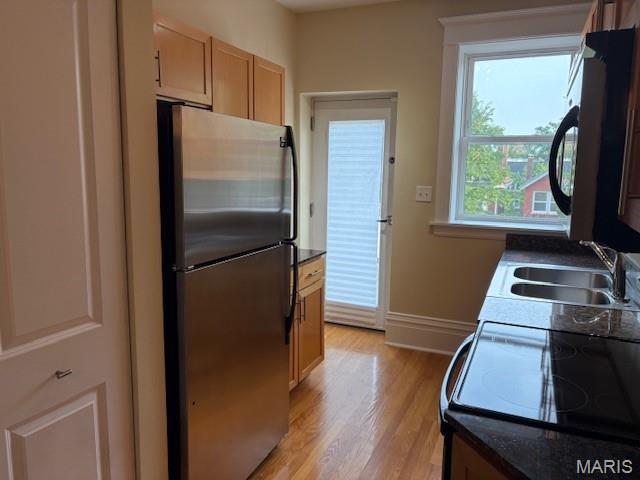 6114 Washington Blvd Unit 302, Saint Louis, MO 63112 - kitchen featuring freestanding refrigerator, a sink, dark countertops, light wood finished floors, and baseboards