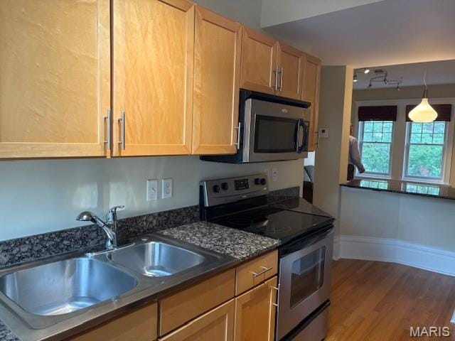 6114 Washington Blvd Unit 302, Saint Louis, MO 63112 - kitchen featuring appliances with stainless steel finishes, a sink, wood finished floors, baseboards, and pendant lighting