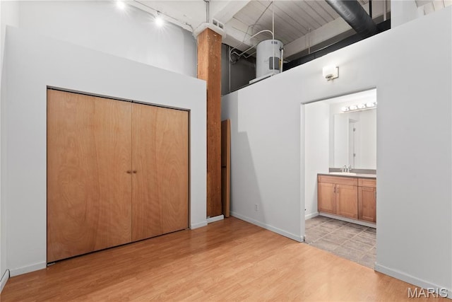 507 N 13th St Unit 207, Saint Louis, MO 63103 - unfurnished bedroom featuring a high ceiling, rail lighting, light wood-type flooring, a closet, and ensuite bath